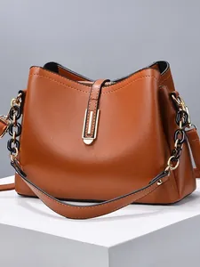 Sac seau en cuir marron avec boucle dorée et chaîne en résine sur support géométrique