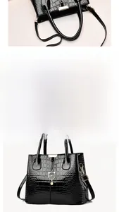 Detail view of black crocodile pattern tote bag with gold hardware and cat charm pendant