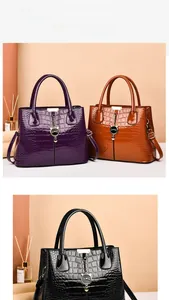 Close-up of three faux crocodile leather handbags with cat-shaped gold charms in various colors