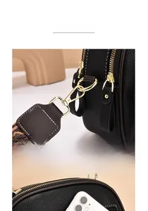 Detail view of black lychee leather bag with gold hardware and jacquard woven strap
