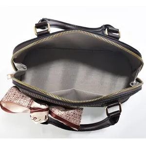 Detail der dunkelbraunen Muschel-Tasche mit Gold-Reißverschluss und Fischgrätfutter