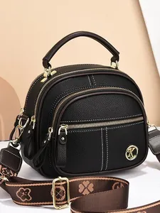 Black pebbled leather crossbody bag with multiple zippers and wide clover pattern strap