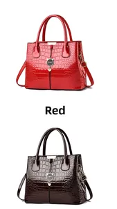 Detail of glossy crocodile pattern handbags in red and brown with metal cat charm