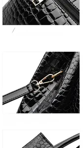 Detail view of glossy crocodile pattern handbag showing metal zipper and hardware buckles