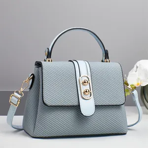 Detail of woven texture flap bag with gold hardware and removable light blue strap