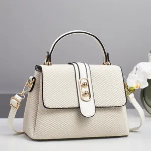 Detail showing creamy woven texture, gold twist lock and smooth leather trim of the bag