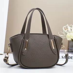 Dettaglio della borsa grigia con texture litchi e barre decorative in metallo oro chiaro
