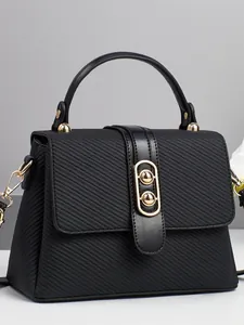 Borsa a mano nera minimalista con dettagli dorati e tessuto testurizzato su sfondo grigio