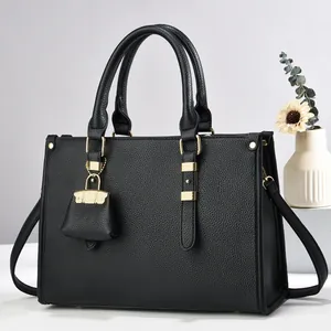 Close-up of black lychee grain tote bag with gold hardware and mini decorative charm