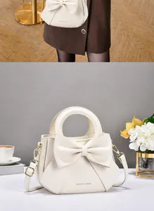Dettaglio elegante borsa a mano color crema con grande fiocco e finiture in metallo oro
