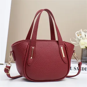 Dettaglio borsa a mano in pelle bordeaux con trama litchi e dettagli in metallo oro