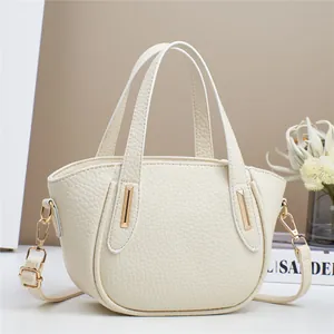 Dettaglio macro della borsa in pelle color crema con eleganti finiture in metallo oro
