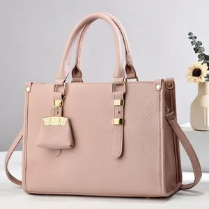 Detailed macro view of pink litchi grain leather tote bag with gold metal chain charm