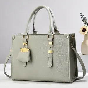 Detail of grey lychee leather tote bag with gold hardware and hanging charm