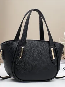 Borsa a mano in pelle martellata nera con fibbie dorate e doppi manici su sfondo elegante