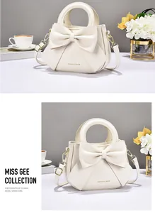 Detailed view of cream PU leather handbag with large bow and golden metal hardware