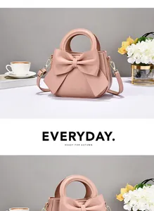 Chic pink handbag with large bow detail and elegant shoulder strap on a cozy desk