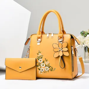 Detail view of yellow handbag set featuring white daisy embroidery and floral pendant