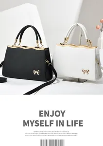 Detail of elegant black and white tote bags with gold bow accents and wave metal trim