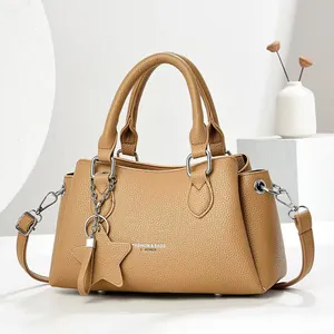 Camel leather handbag with star pendant and detachable strap on a minimalist pedestal