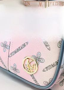 Detailed macro view of the gold logo buckle and printed textured leather on a pink bag