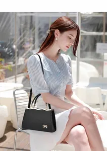 Close-up of black crossbody bag featuring a golden bow metal ornament and Saffiano texture