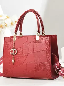 Red embossed faux leather tote bag with wide shoulder strap and gold hardware accents