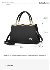 Detail view of black trapezoid handbag with gold hardware and 30x10x19cm dimensions