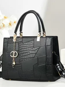 Black embossed leather tote bag with patchwork texture and gold charm accessory