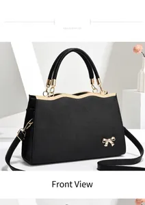 Detail of black cross-grain leather handbag with golden wavy trim and bow accent