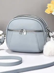 Minimalist light blue shell crossbody bag with triple zippers and faux fur pompom charm