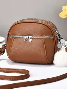 Brown mini shell bag in soft lychee leather with triple zipper compartments and plush charm