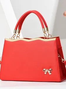 Red Saffiano leather tote bag with golden bow hardware and top handles in 45-degree view