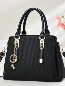 Black leather tote bag with elegant clover pendant and gold-tone metal hardware