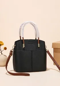 Detail view of black litchi texture leather bucket bag with adjustable brown shoulder strap