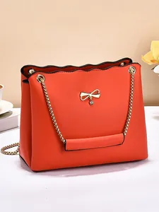 Elegant coral orange leather shoulder bag with gold bow clasp and chain strap