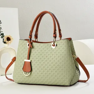 Close-up of woven texture on green tote bag with brown leather handle and gold hardware
