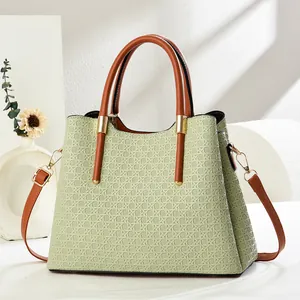 Detail of light green woven texture handbag with brown leather strap and gold hardware
