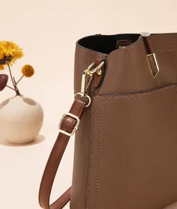 Detailed close-up of brown litchi pattern leather with gold metal zipper and strap hook