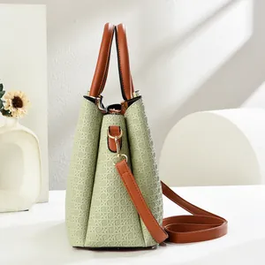 Detail view of woven light green handbag with brown handle and textured accordion side design