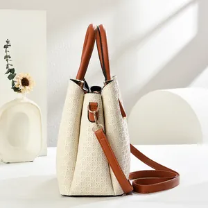 Detail of star-patterned beige tote bag showing brown straps and gold metal hardware