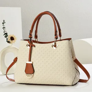 Close-up of woven texture handbag with brown leather straps and gold metal details