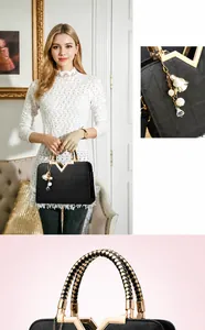 Détail du sac cabas noir avec motif matelassé, boucle en V dorée et breloque florale