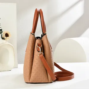Detail view of woven leather texture on a brown handbag with gold hardware and shoulder strap