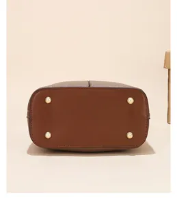 Detail view of the brown bucket bag base with four golden anti-wear metal studs