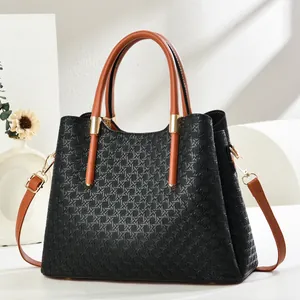 Detail of black woven texture handbag with contrasting brown straps and gold hardware
