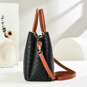 Macro shot of stylish black woven texture handbag with dual brown straps and gold hardware