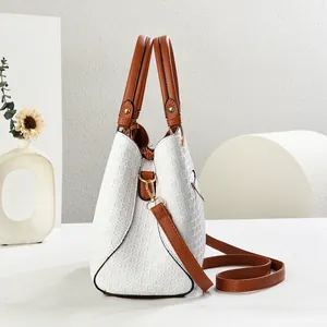 Close-up of woven texture handbag with caramel brown strap and gold metal hardware