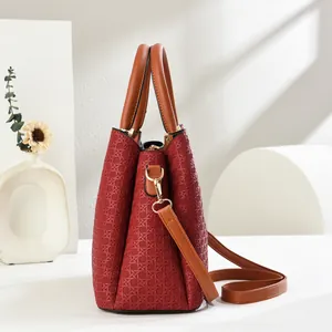 Close-up of wine red woven texture handbag with brown handles and gold hardware