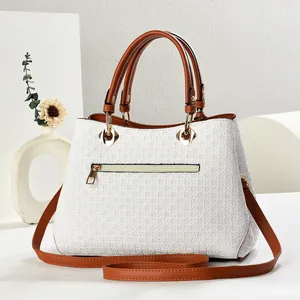 Detail shot of the white woven texture and brown leather handle on a stylish handbag